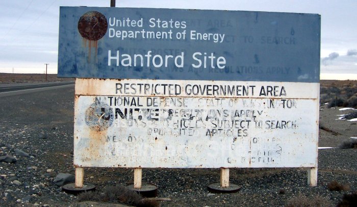 [Image Description: A weathered sign posted by the United States Department of Energy, titled "Hanford Site" and reading "RESTRICTED GOVERNMENT AREA," followed by unintelligible text.]